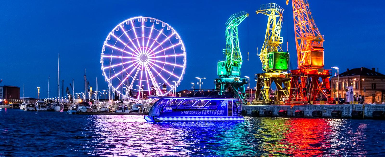 Party Boat nocą na Odrze, w tle koło widokowe i dźwigi na Łasztowni